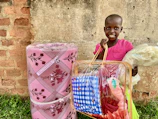 A cheerful child opening a package filled with creative craft materials at home.