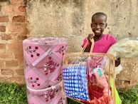 A smiling child holding a bag of fresh groceries received through our food distribution program.