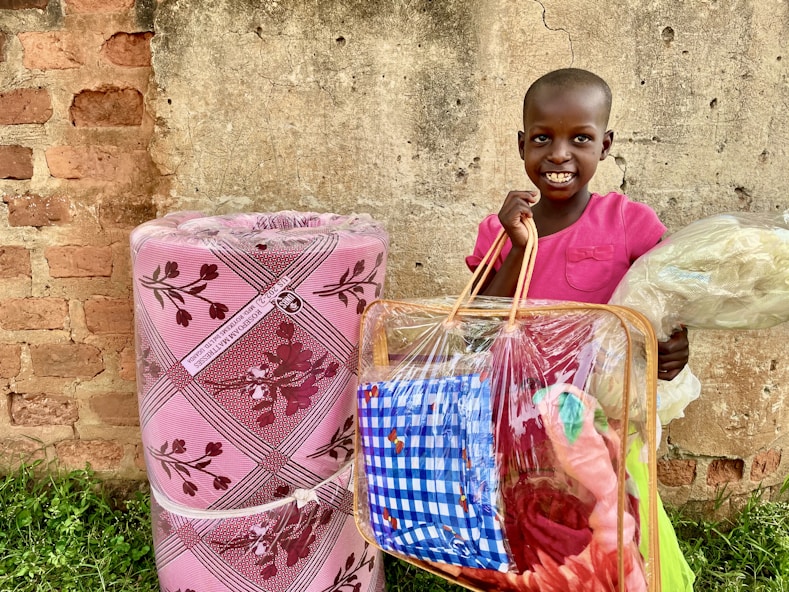A smiling child holding a backpack filled with colorful school supplies.