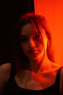 A slow-motion shot of a model in crimson silk, lit by soft smoky plum shadows and glowing warm gold highlights.