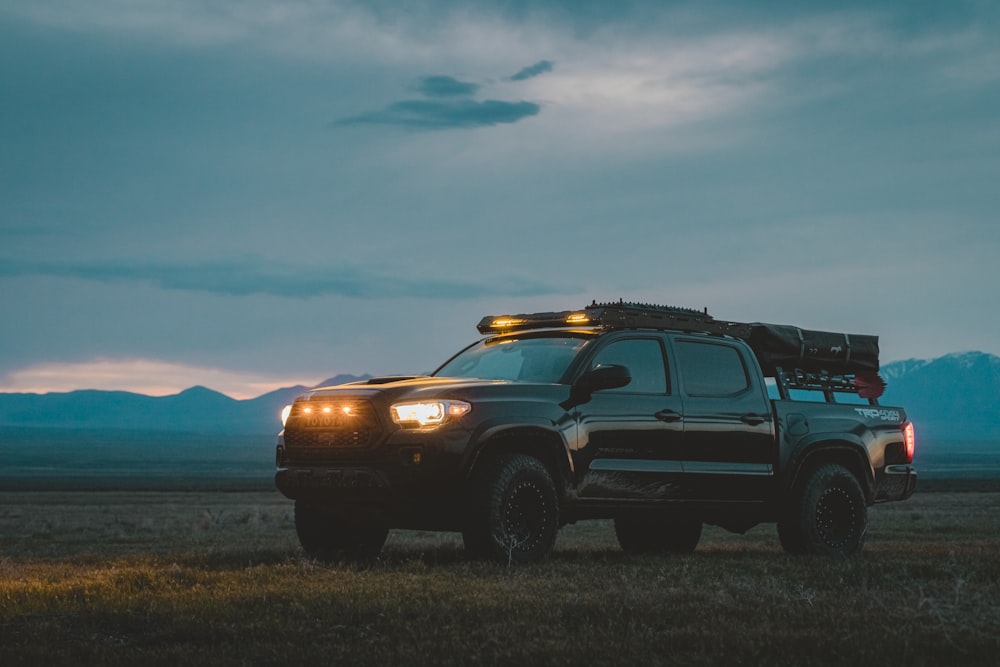 a truck parked in a field with mountains in the background