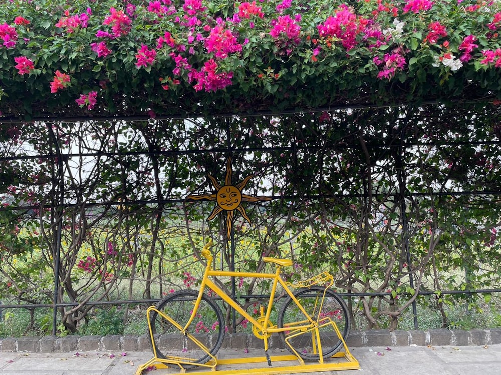 a yellow bicycle parked next to a fence