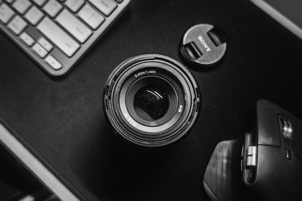 uma lente de câmera sentada em cima de uma mesa ao lado de um teclado