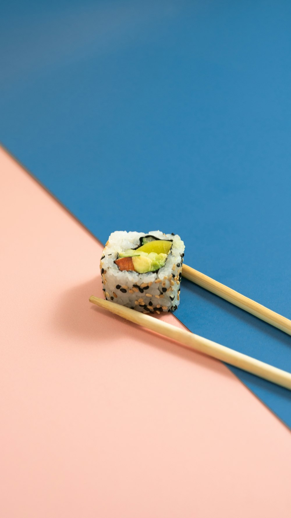 two chopsticks with sushi on them on a blue and pink background