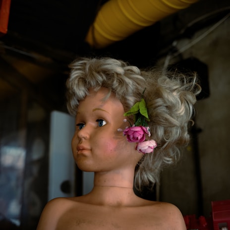 A curly blonde wig styled loosely, resting on a soft fabric background.