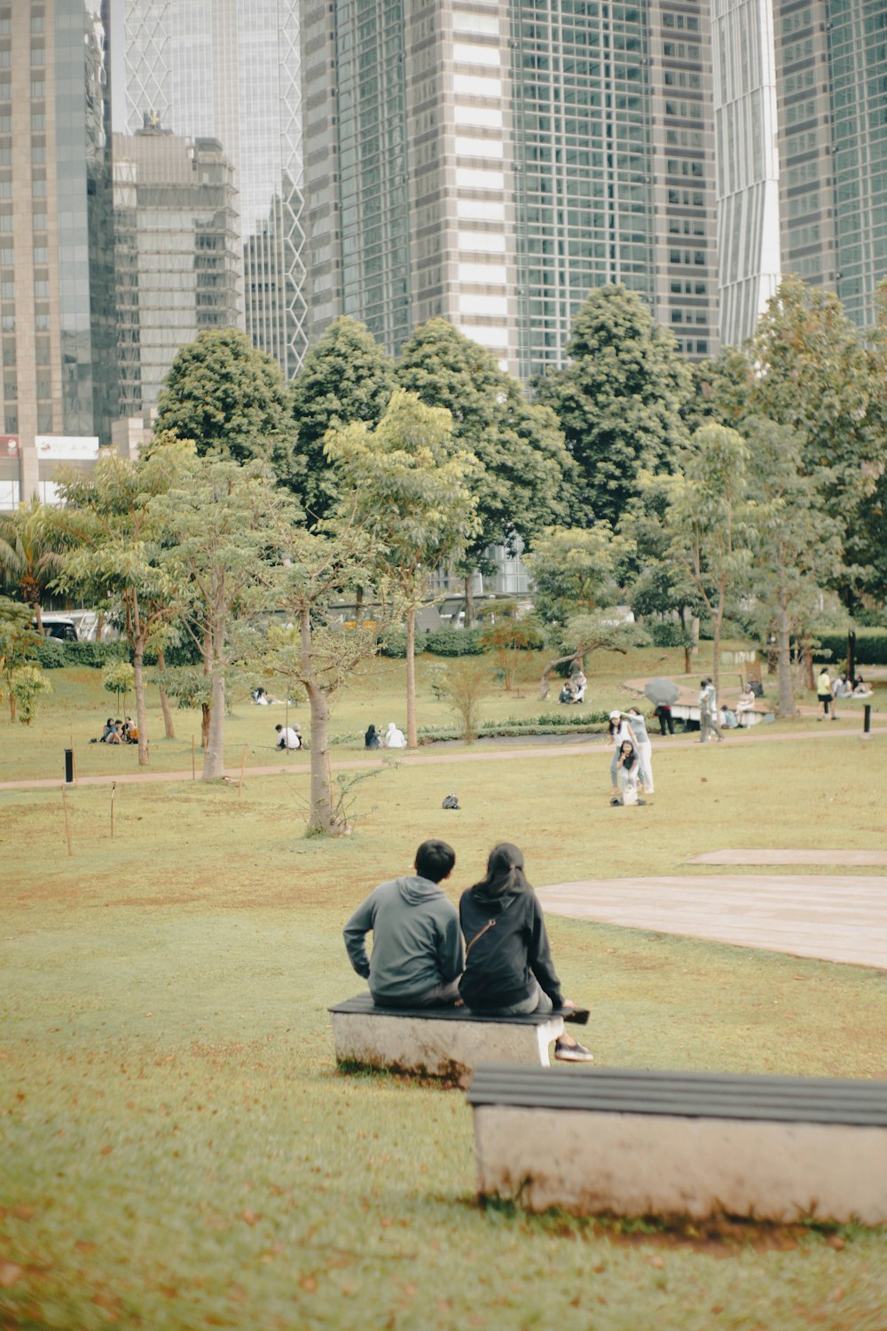 two people sitting on a bench in a park