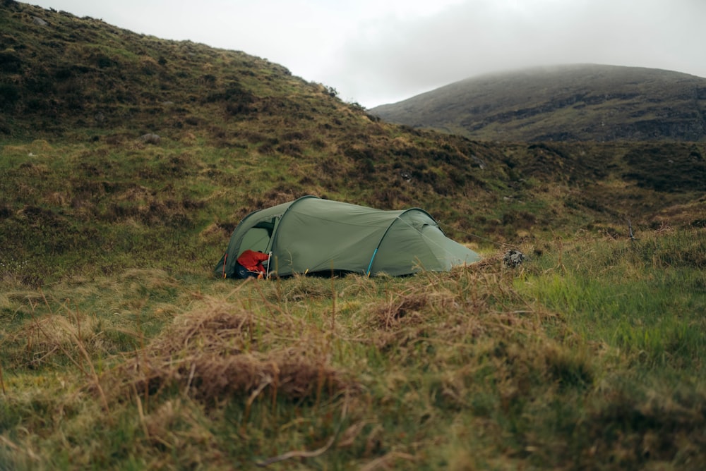 a tent pitched up on a grassy hill