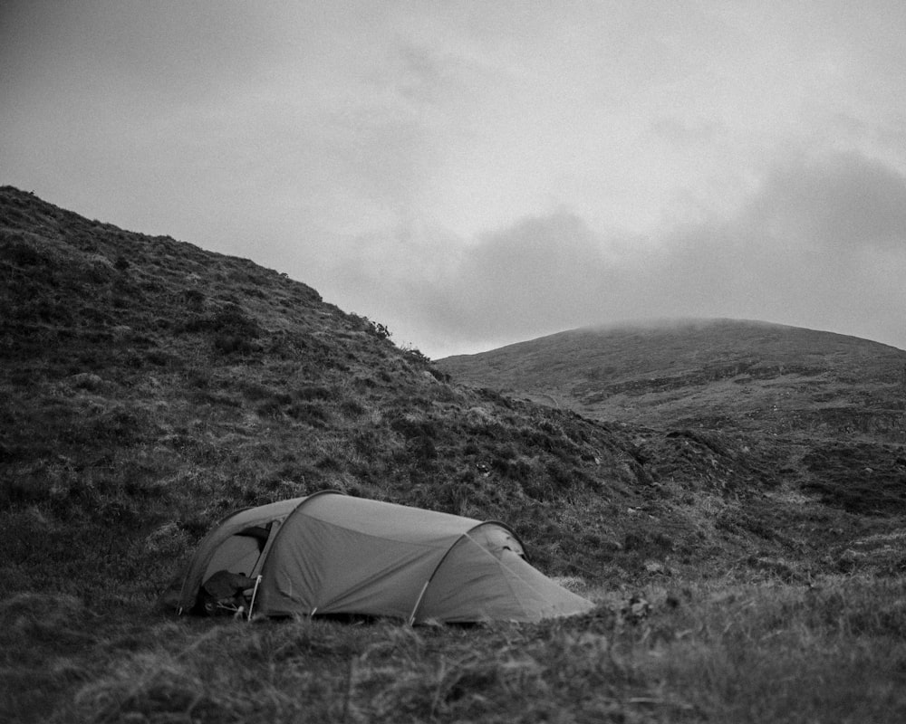 a tent pitched up on a grassy hill