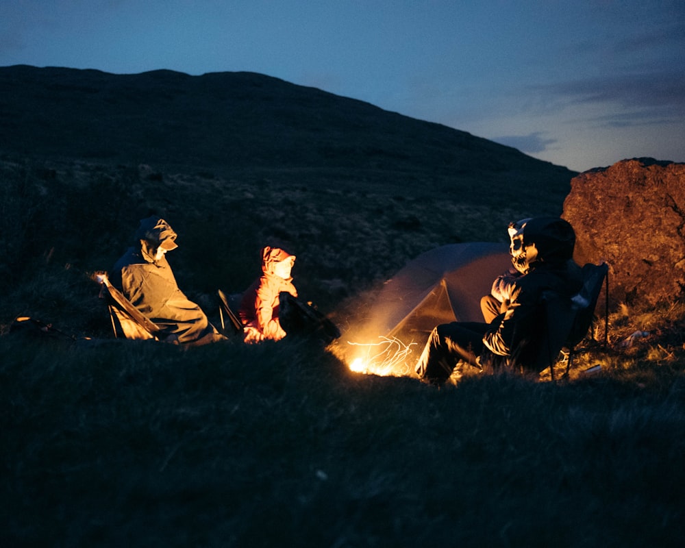 a group of people sitting around a campfire