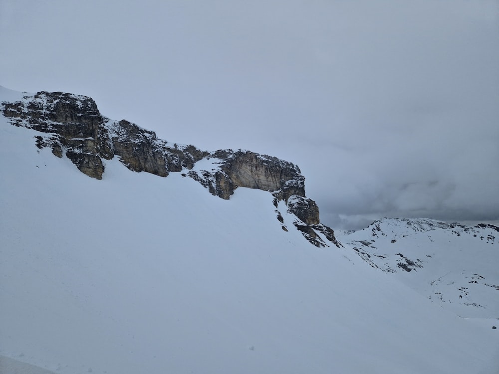 uma montanha coberta de neve com um penhasco ao fundo