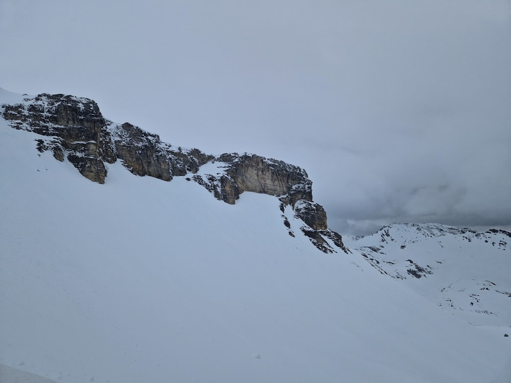 a mountain covered in snow with a cliff in the background