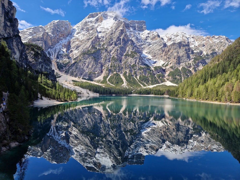 a mountain range is reflected in the still water of a lake