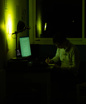 A focused professional writing a proposal at a clean, modern desk with a laptop and notes.