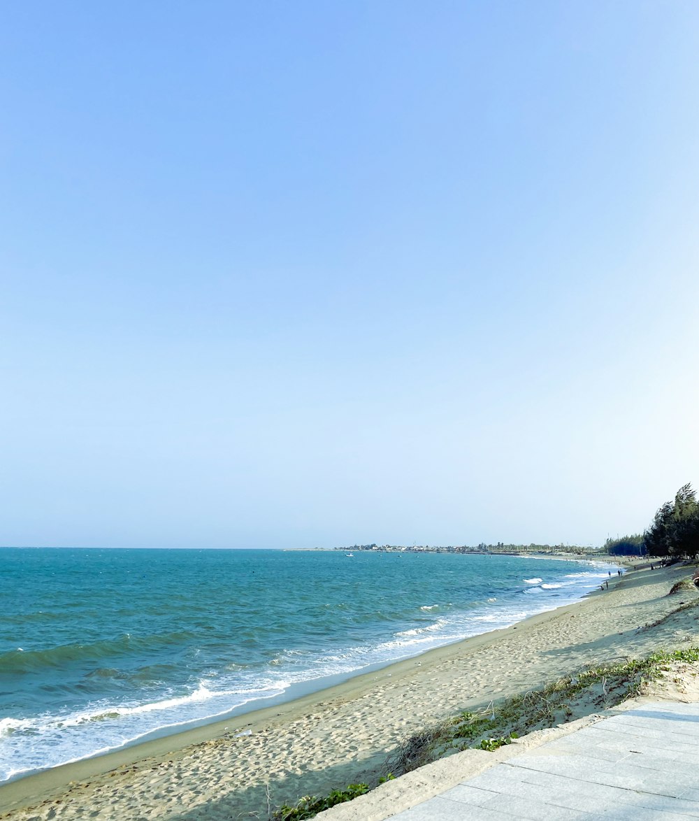 a bench sitting on the side of a beach next to the ocean