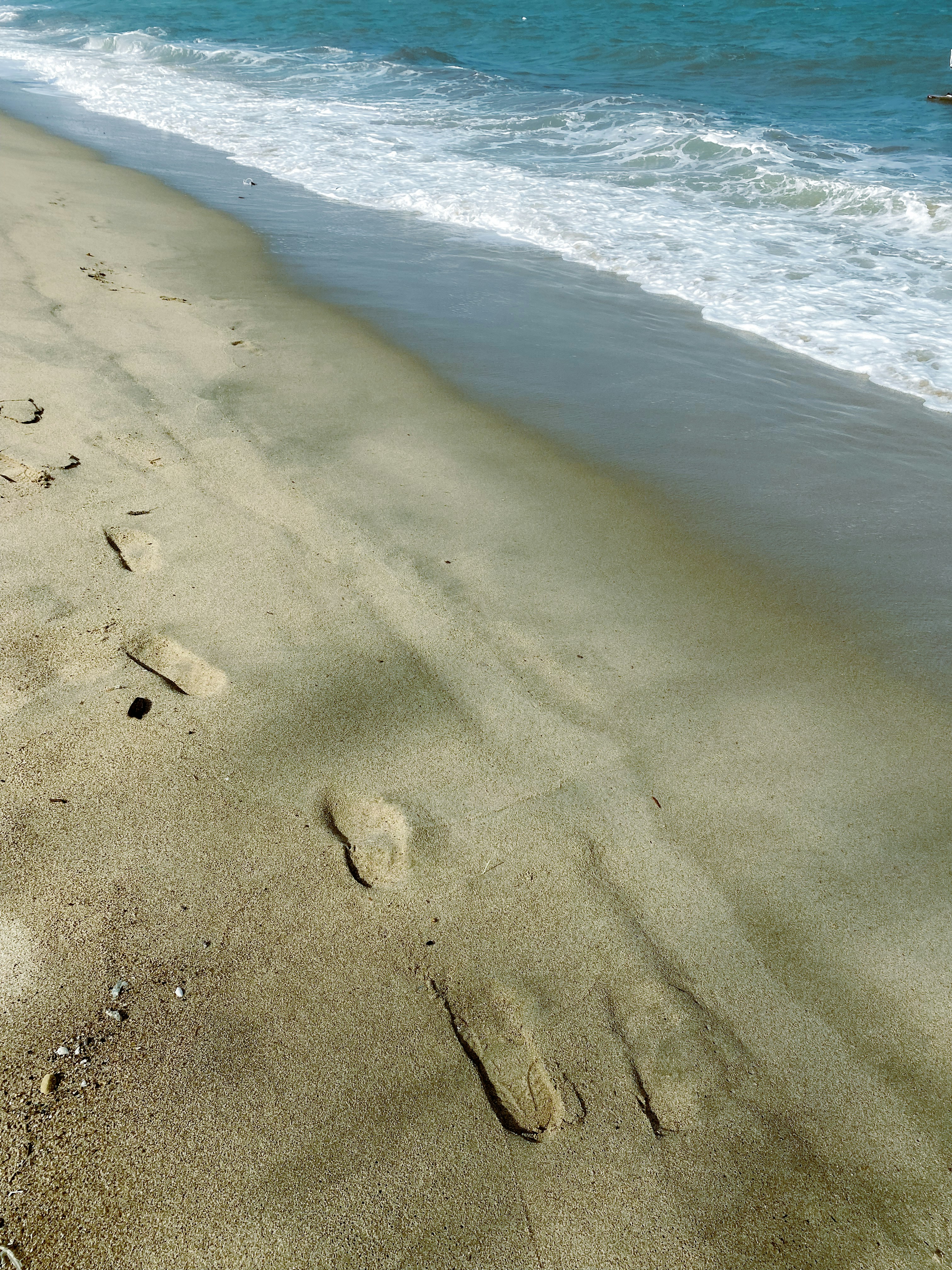 footprints in the sand on a beach next to the ocean