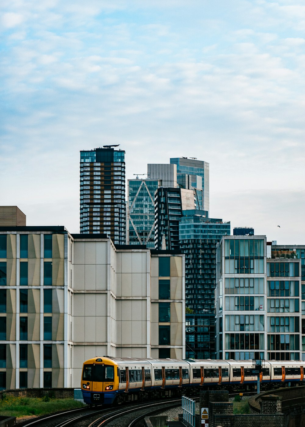 a yellow train traveling through a city next to tall buildings