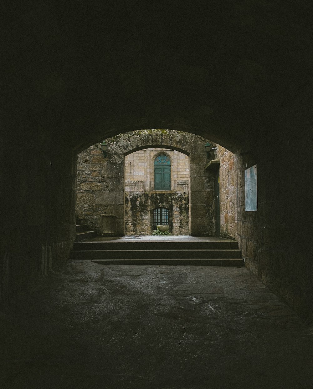 un tunnel sombre avec des marches menant à une porte verte