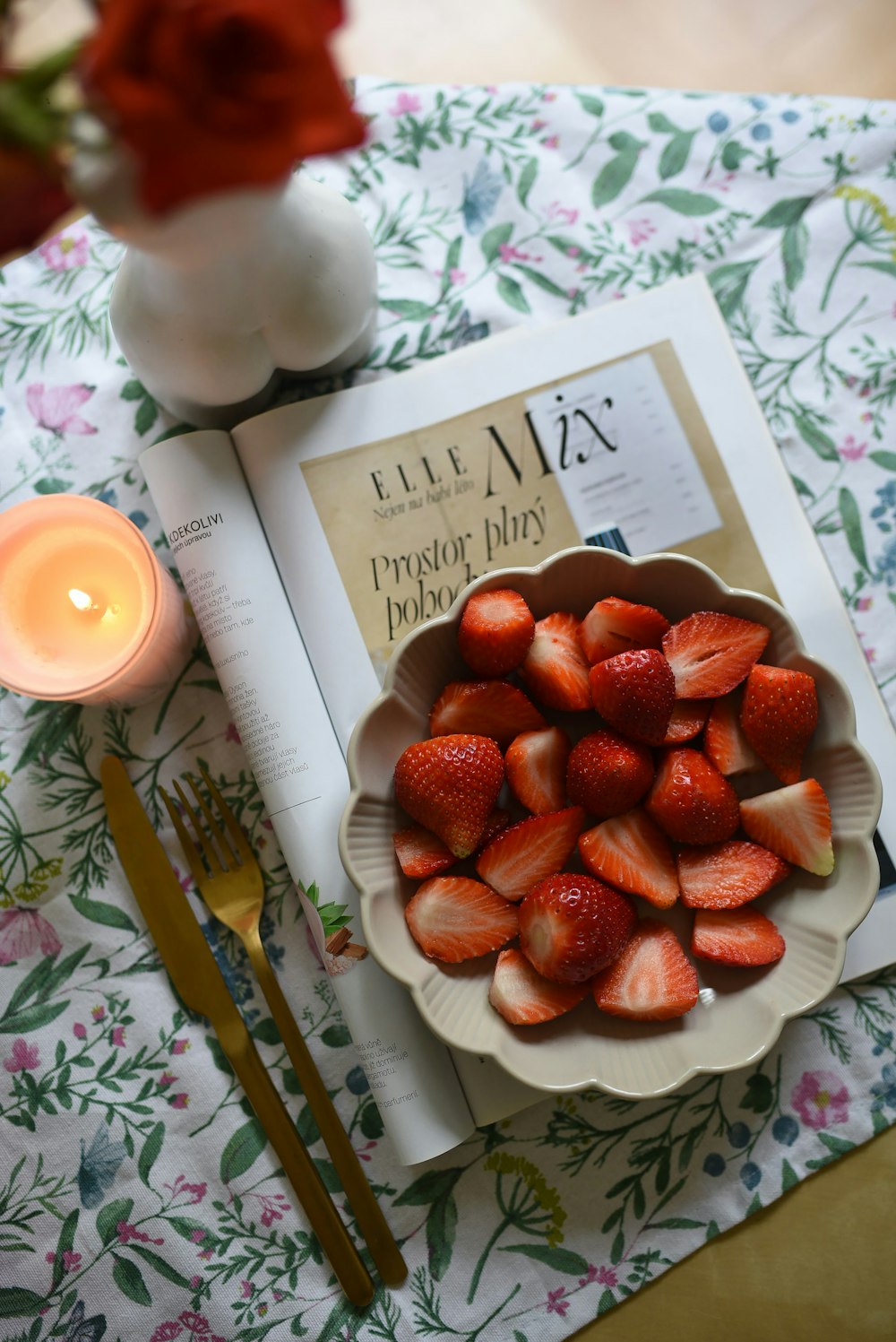 a plate of strawberries next to a candle and a book