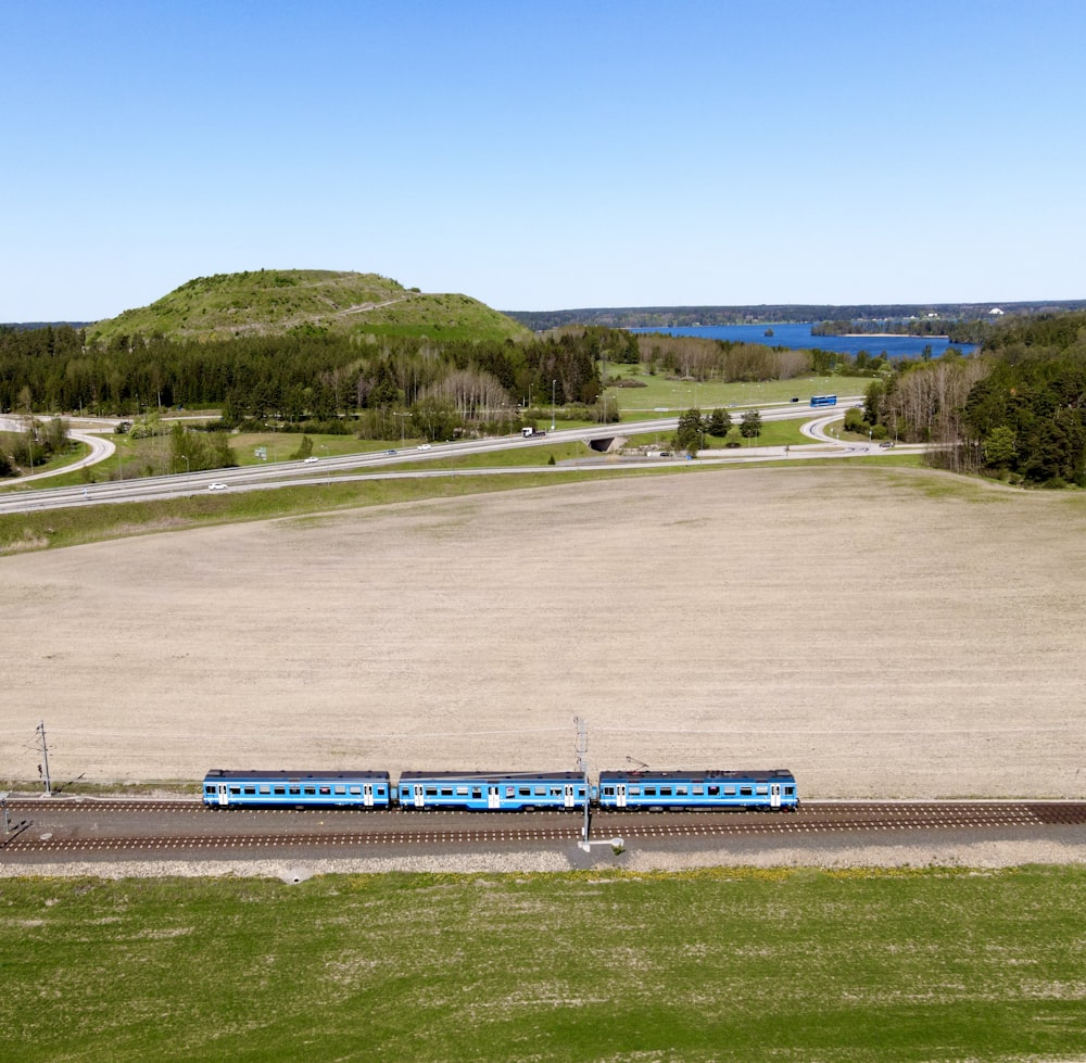 a blue train traveling through a rural countryside