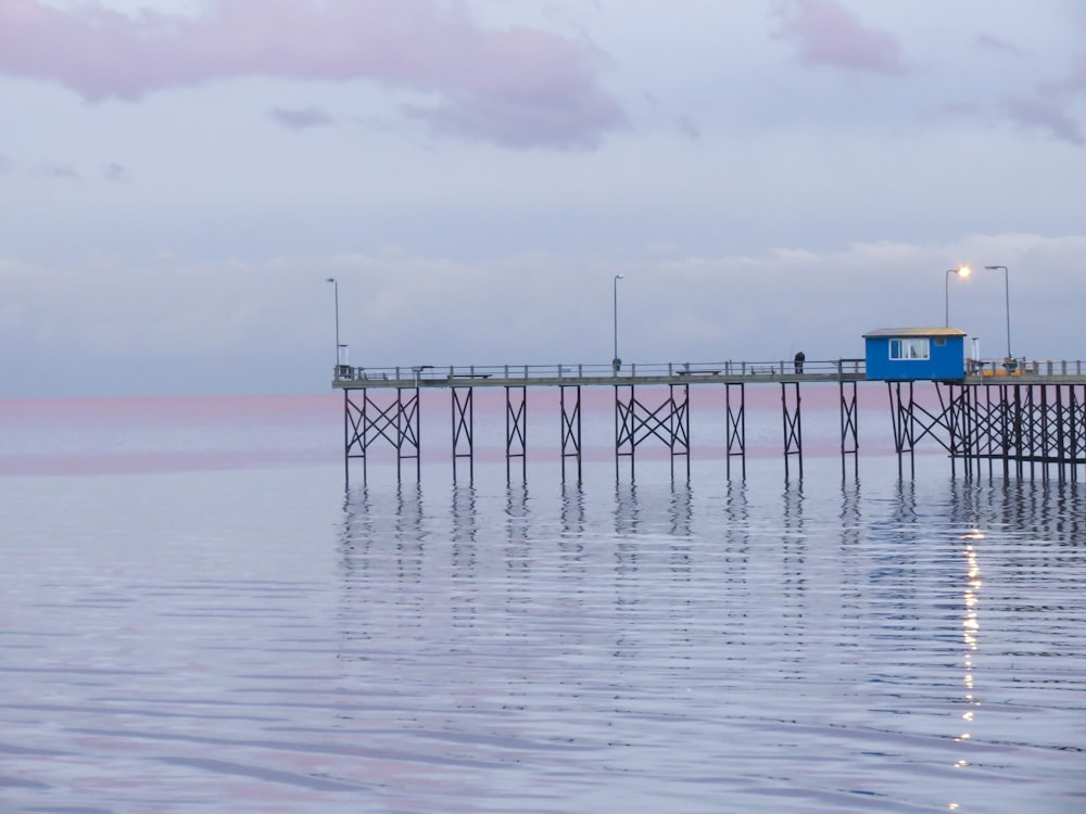 a pier on the water with a blue building in the background