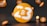 A large orange disc with the number 23 prominently displayed in white, accompanied by the Bitcoin symbol. Smaller orange discs with Bitcoin symbols surround the main disc, all set against a dark background.