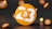 A large orange disc with the number 23 prominently displayed in white, accompanied by the Bitcoin symbol. Smaller orange discs with Bitcoin symbols surround the main disc, all set against a dark background.