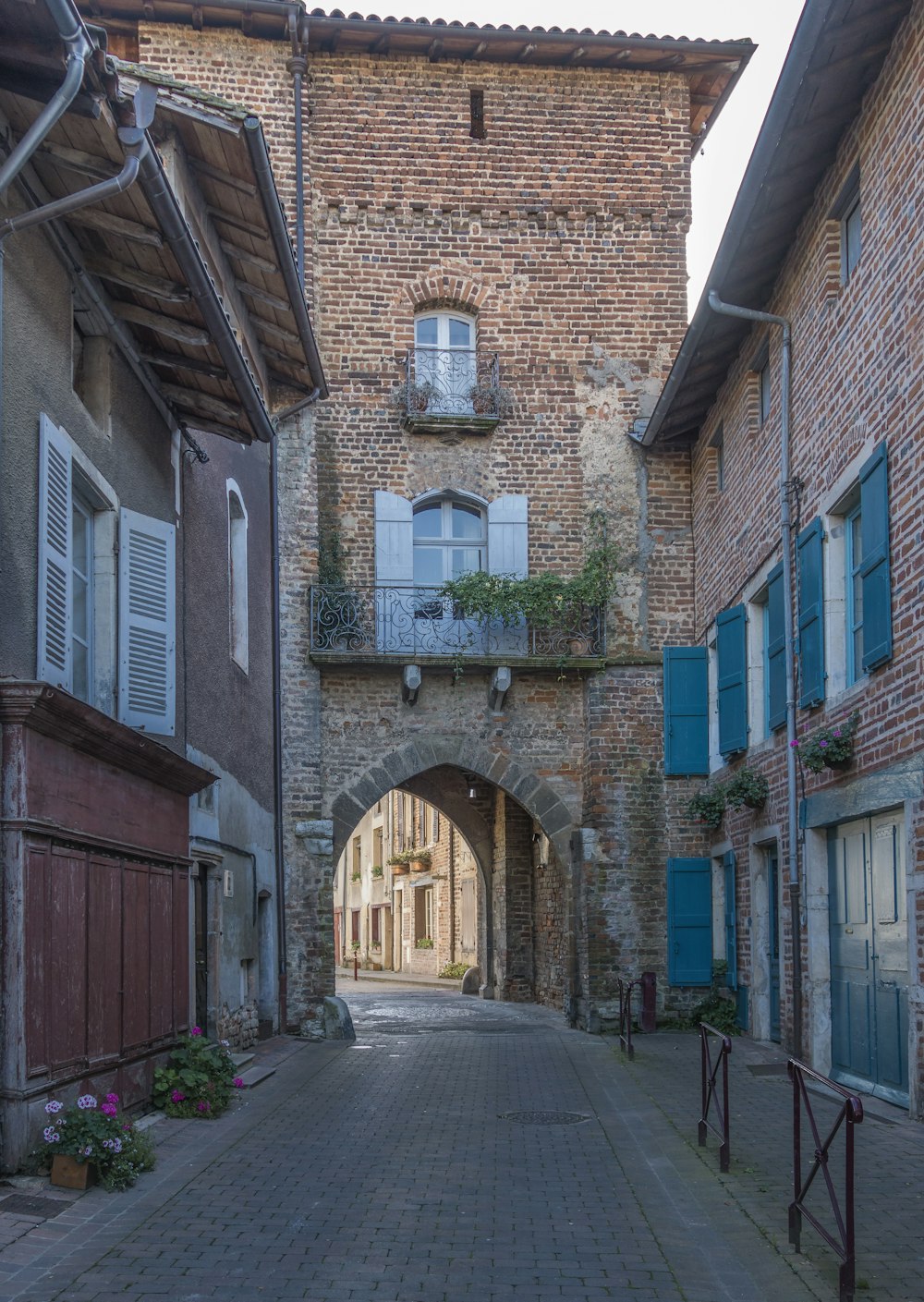 an alley way with a brick building and blue shutters