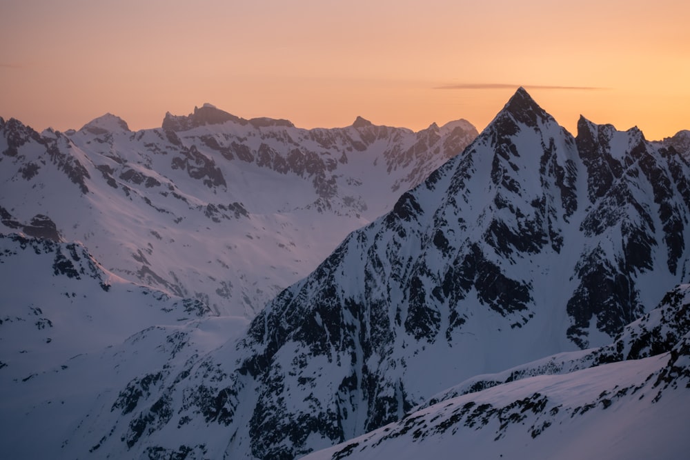 a snowy mountain range with a sunset in the background