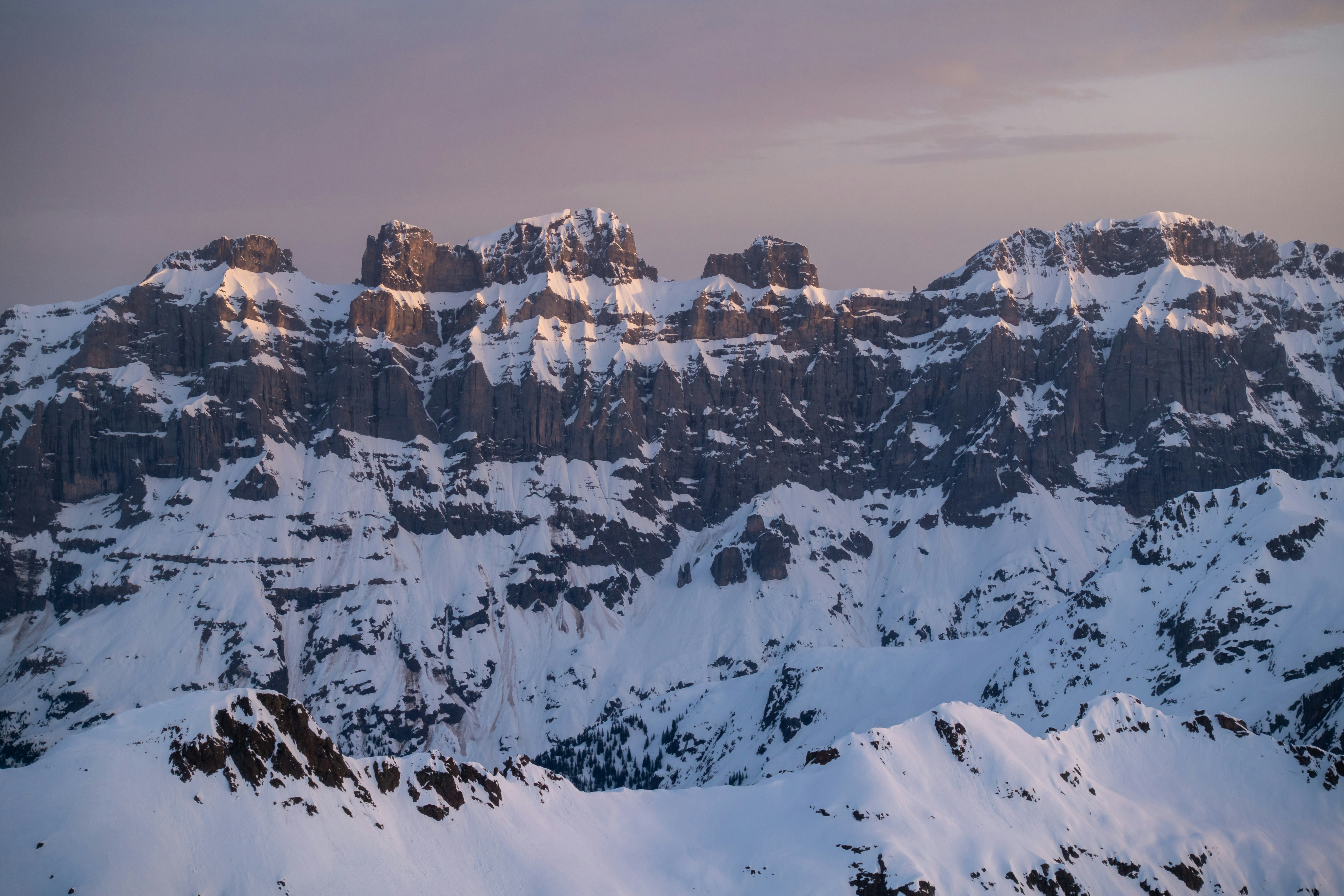 a mountain range covered in snow under a cloudy sky