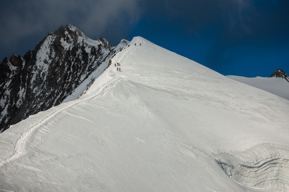 a group of people climbing up the side of a snow covered mountain