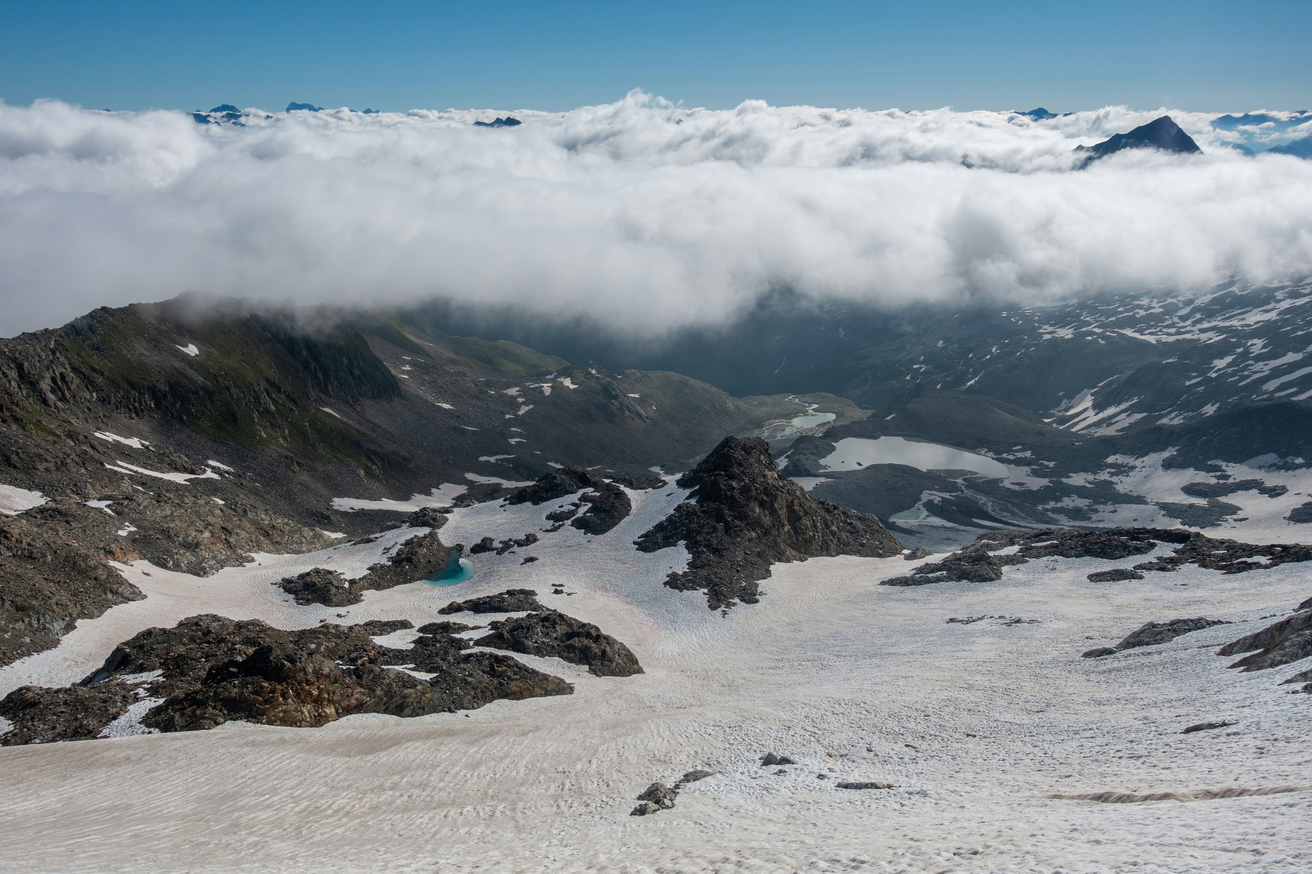 a snow covered mountain with a few clouds in the sky