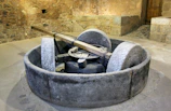 Close-up of a traditional olive mill stone grinding olives in a rustic setting.
