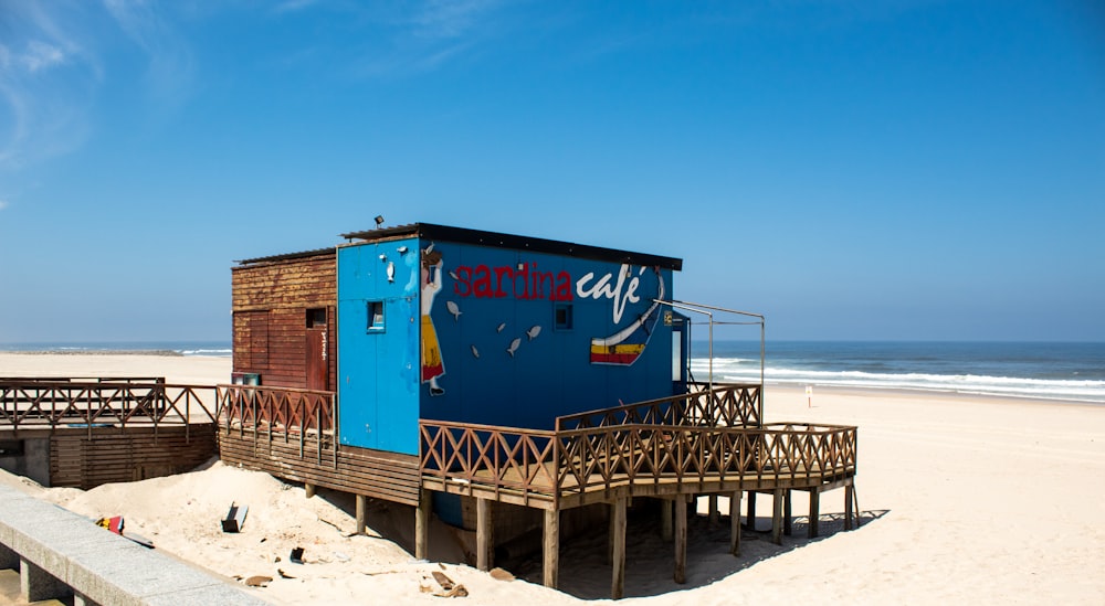 a small blue building sitting on top of a sandy beach
