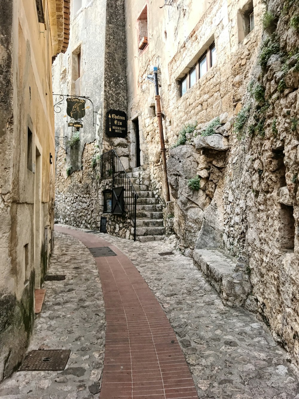 a narrow street with stone buildings and a brick walkway