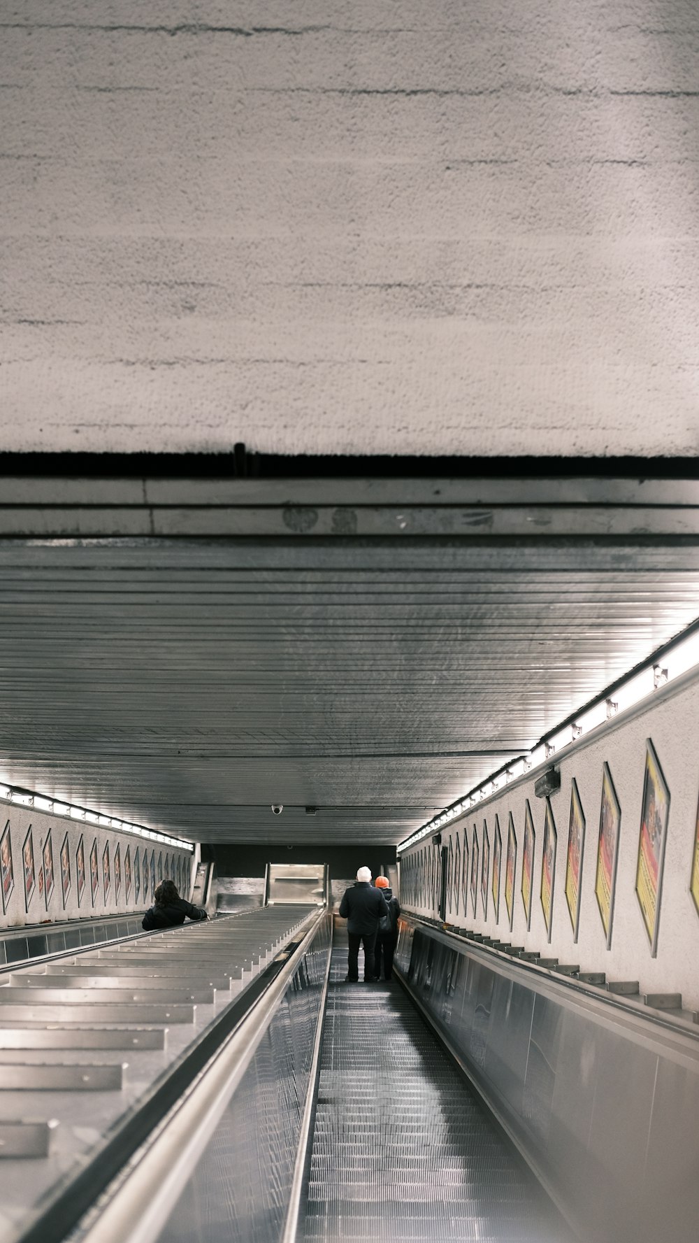 a couple of people walking down a long escalator