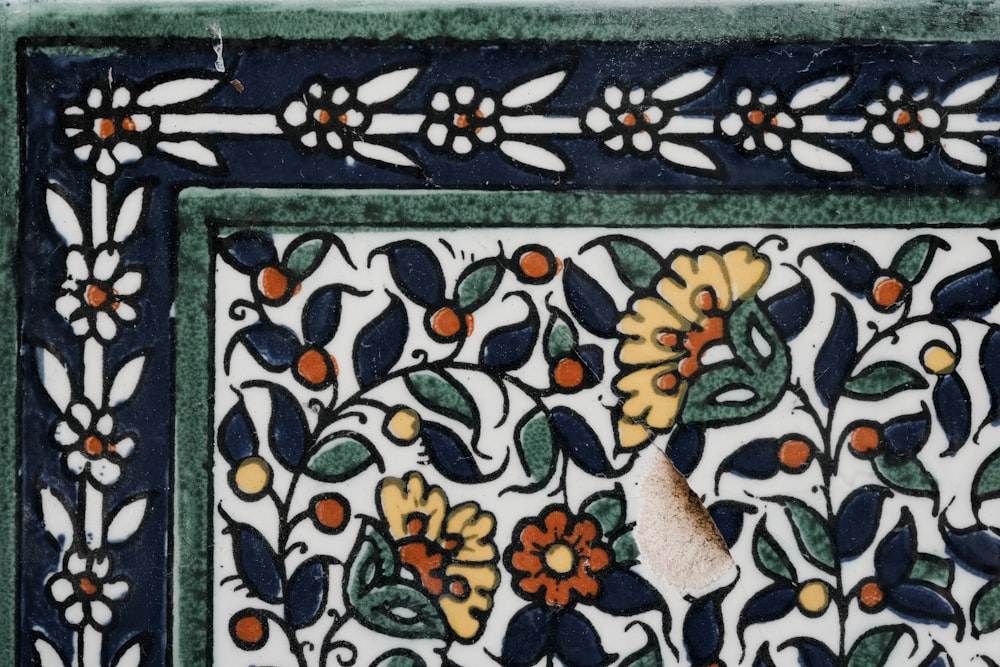 a close up of a tile with flowers and leaves