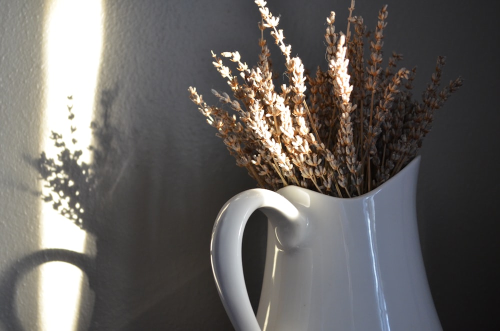 a white vase with dried plants in it