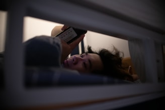 a woman laying in bed holding a remote control