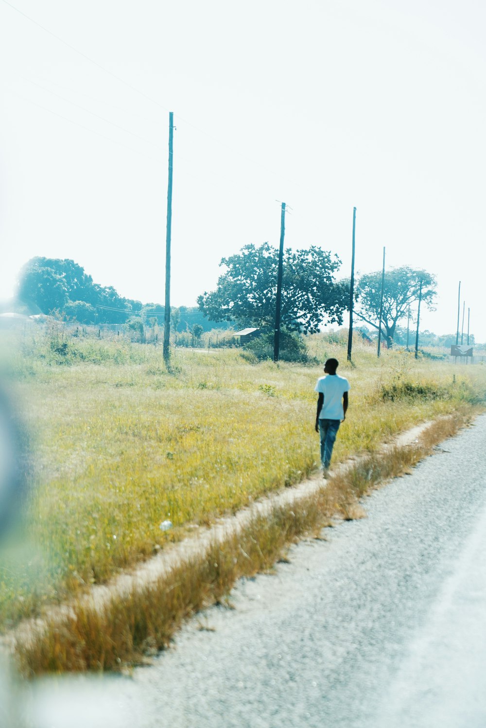 a man walking down a road next to a field
