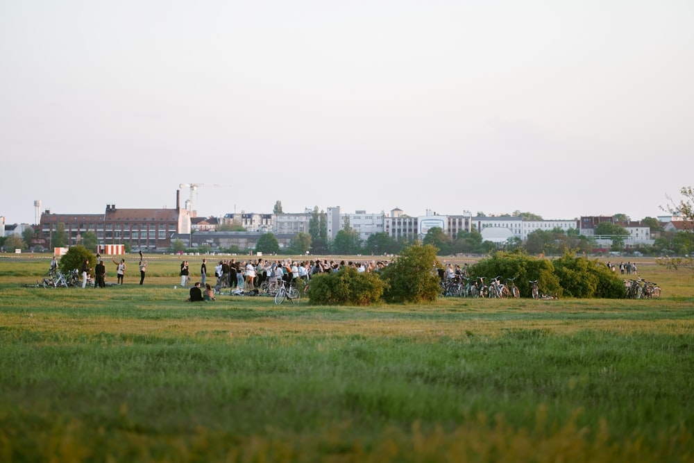 a group of people in a field with buildings in the background