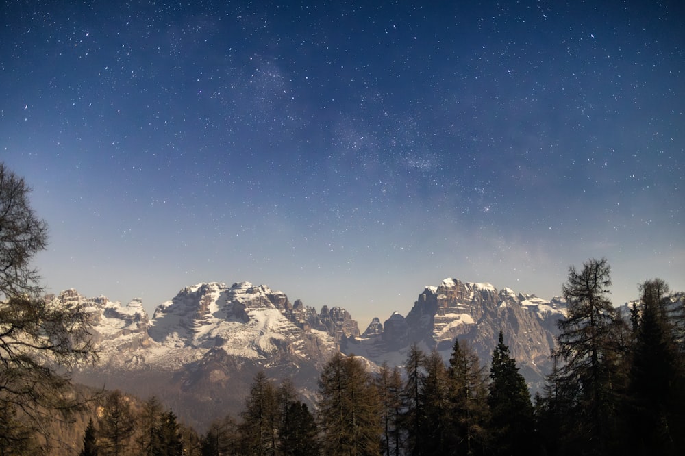 a night sky with stars above a mountain range