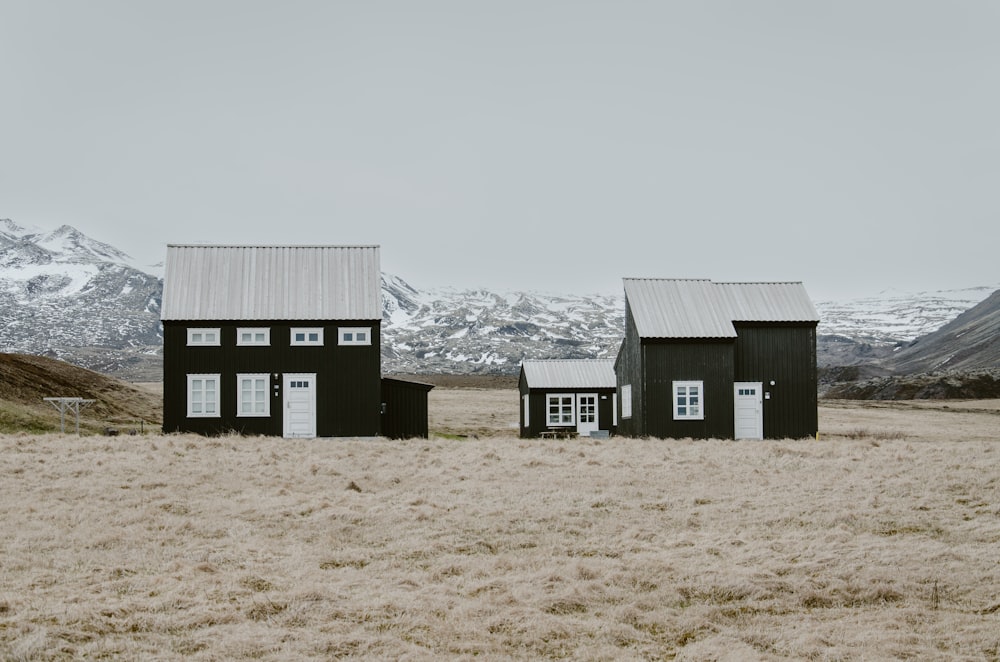 a couple of black buildings sitting on top of a dry grass field