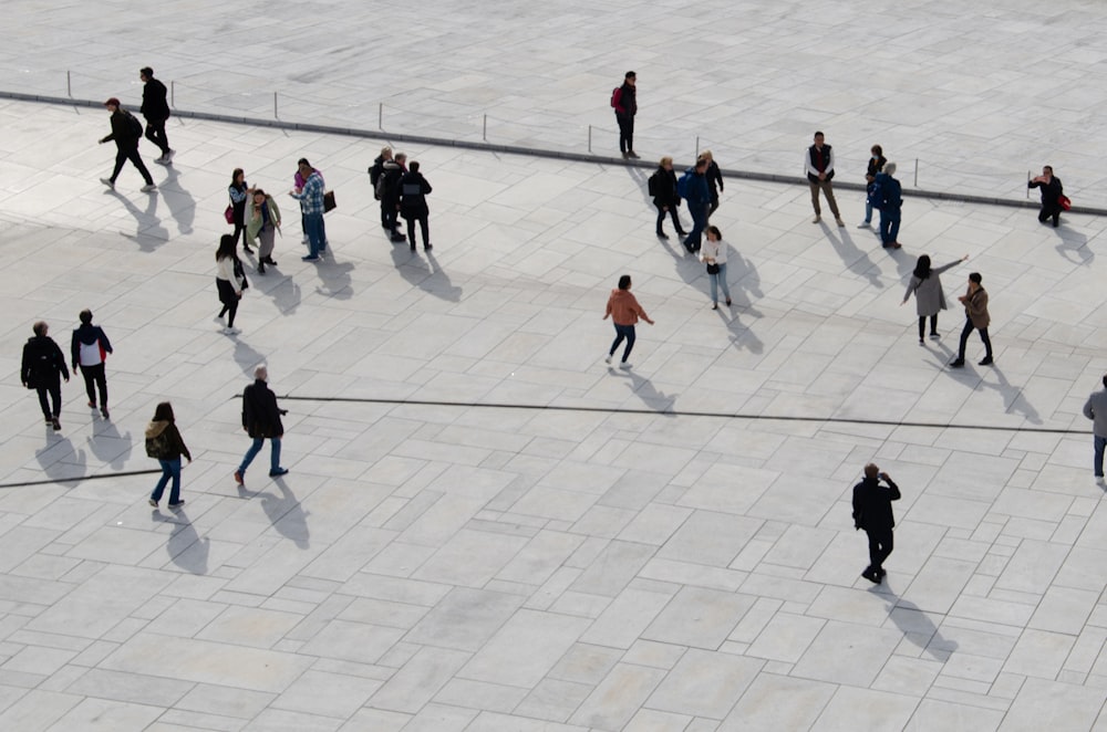 a group of people walking across a cement walkway