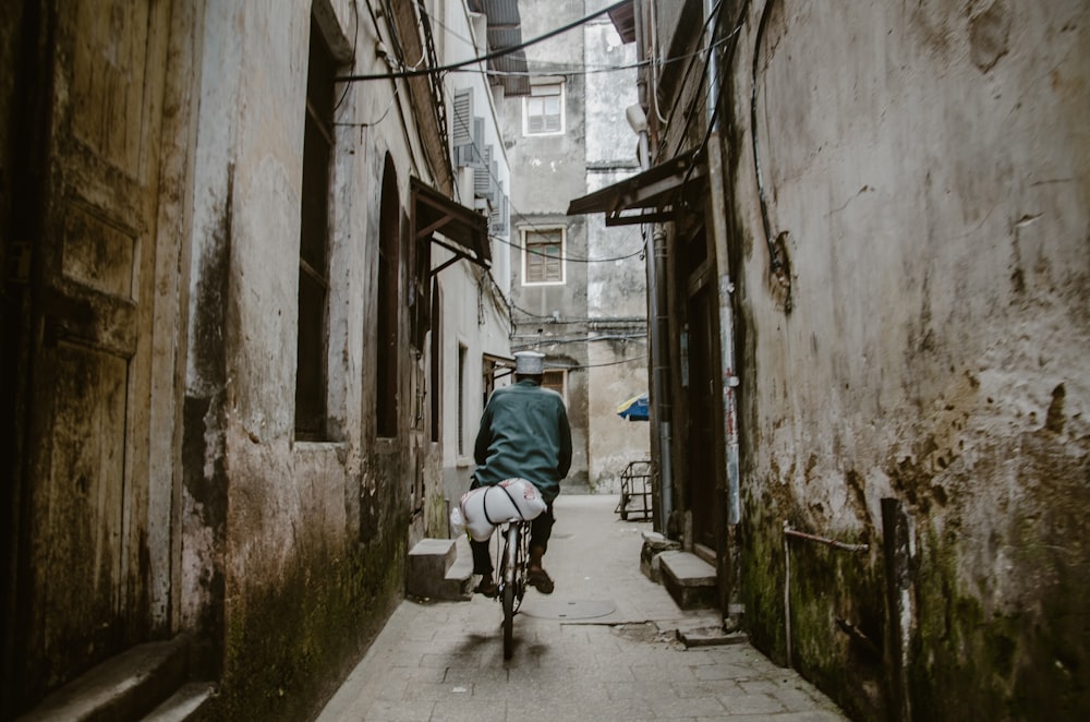 a man riding a bike down a narrow alley way