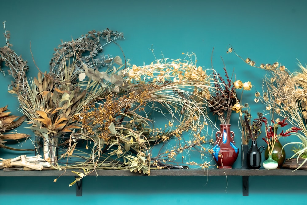 a shelf filled with vases and plants on top of a blue wall