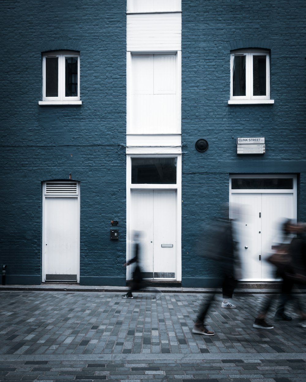 a couple of people walking past a blue building
