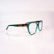 A pair of eyeglasses with a distinctive design, featuring green transparent frames with brown tortoiseshell accents on the temples. The glasses are set against a plain, soft-focus background, highlighting their stylish and modern appearance.