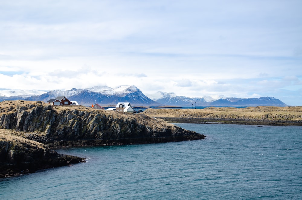 a body of water surrounded by mountains and grass