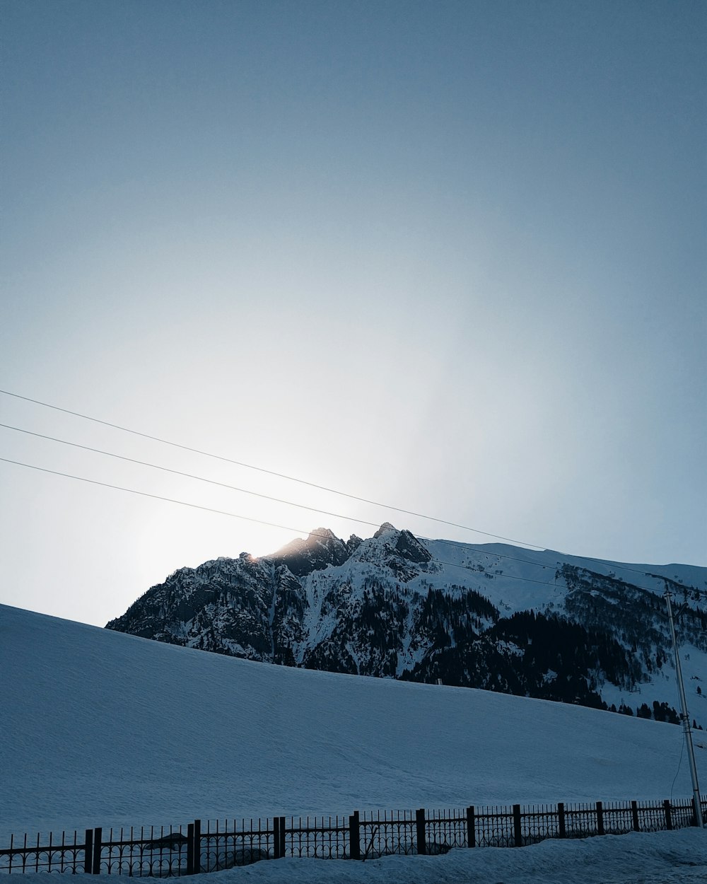 a snow covered mountain with a fence in the foreground