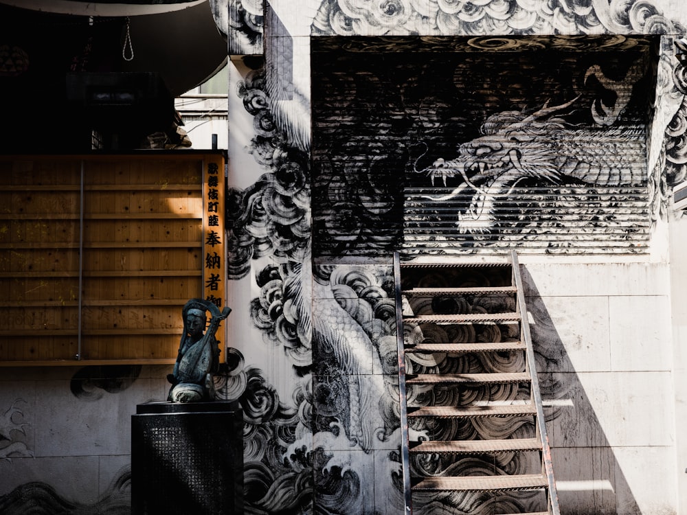 a stair case next to a wall with a dragon painting on it